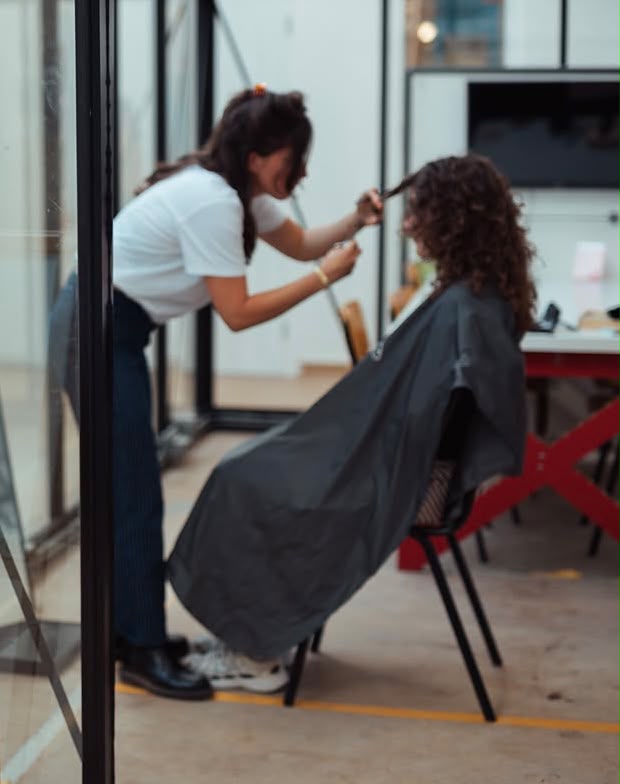 Nada knipt het haar van een klant bij De Filosofische Kapper.